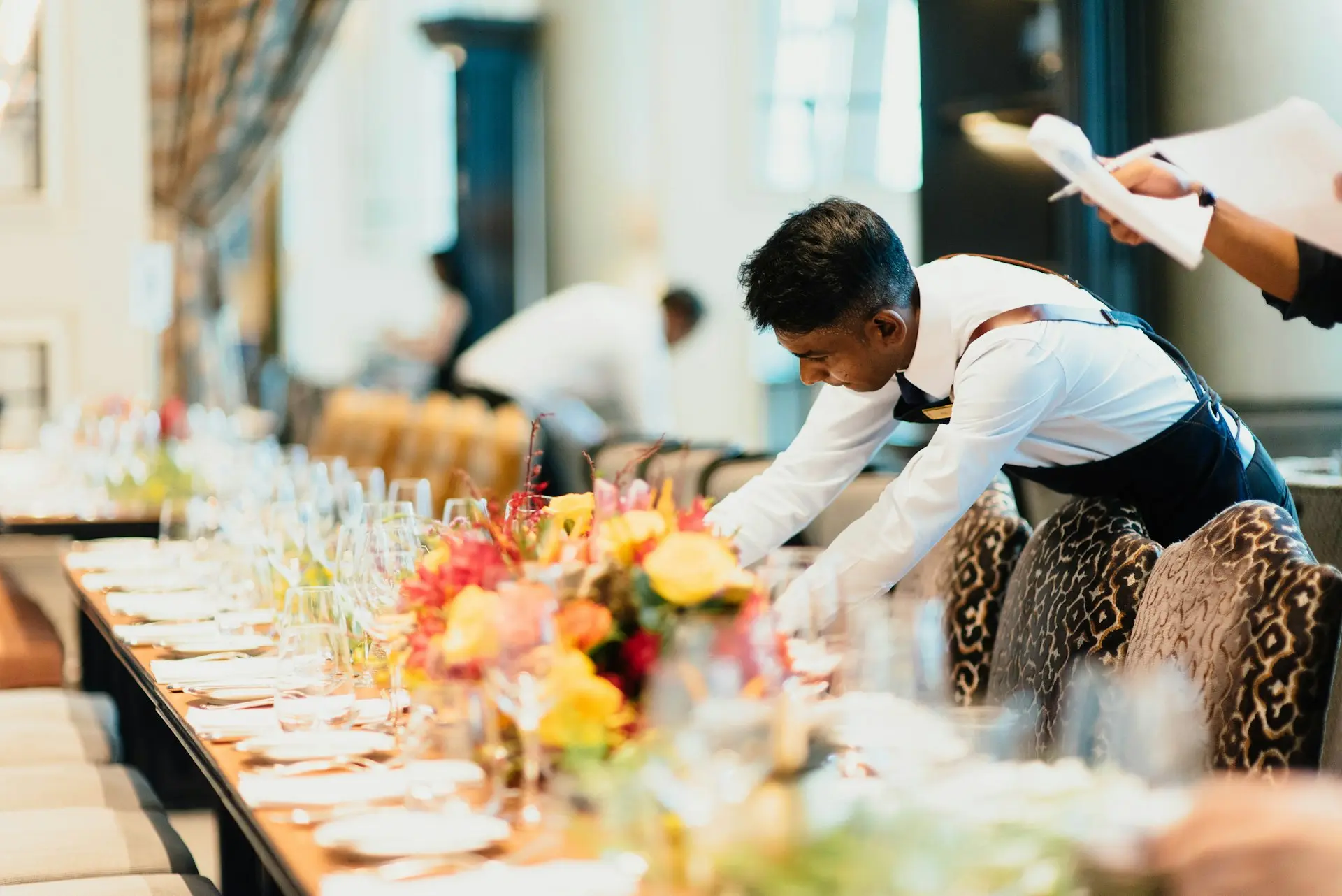 man in white top standing next to table